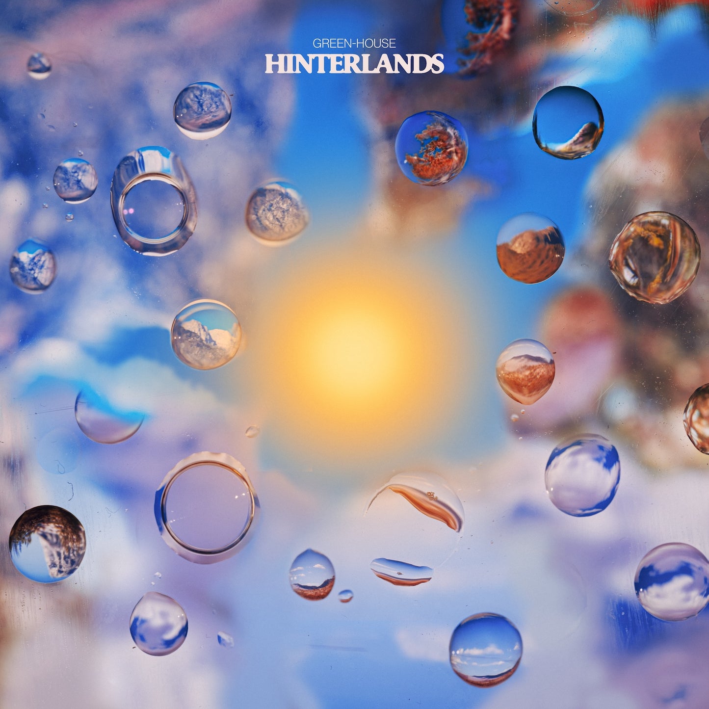 Hinterlands album cover featuring water droplets with reflections and a blurred sunlit background.