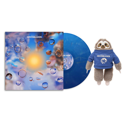 Hinterlands vinyl record with colorful abstract cover and a plush sloth toy wearing a blue Hinterlands hoodie
